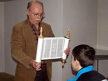 Peter Steinhäuser zeigt den Schülern und Schülerinnen die Torarolle mit den religiösen Texten. Rechts Leon Hellgoth. Foto: Susanne Deuerling