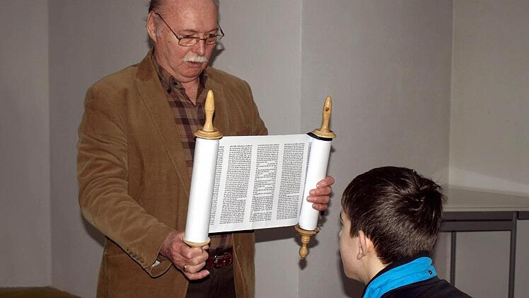Peter Steinhäuser zeigt den Schülern und Schülerinnen die Torarolle mit den religiösen Texten. Rechts Leon Hellgoth. Foto: Susanne Deuerling