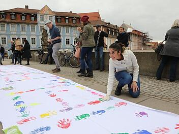 Mit farbigen Händen drucken die Demonstranten ihre Botschaft auf ein weißes Banner.  Foto: Barbara Herbst