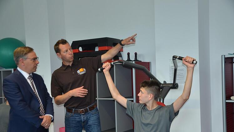 Vorführung an einem Krafttrainingsgerät im neuen Fitnessraum an der Realschule: Der Schüler Tim Maier trainiert, sein Lehrer Felix Pitroff erklärt und Landrat Alexander Tritthart lauscht.  Fotos: Bernhard Panzer
