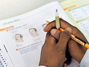 Das Lehrbuch "Deutsch im Alltag" liegt in einem Deutschkurs für Flüchtlinge i vor einem jungen Mann auf der Schulbank. Foto: Hendrik Schmidt/dpa