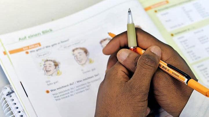 Das Lehrbuch "Deutsch im Alltag" liegt in einem Deutschkurs für Flüchtlinge i vor einem jungen Mann auf der Schulbank. Foto: Hendrik Schmidt/dpa