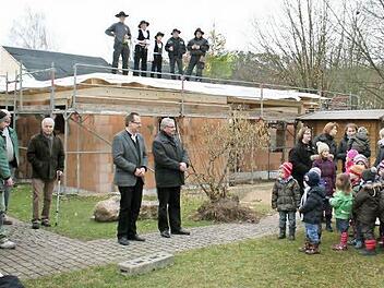 Oben auf dem Dach sagte Zimmerermeister Georg Hemmerlein (Zweiter von links) seinen Richtspruch. Unten freuten sich Diakon Burkard Farrenkopf und Zweiter Bürgermeister Fritz Stütz (Mitte von links) über das Lied der Kindergartenkinder.  Foto: Evi Seeger
