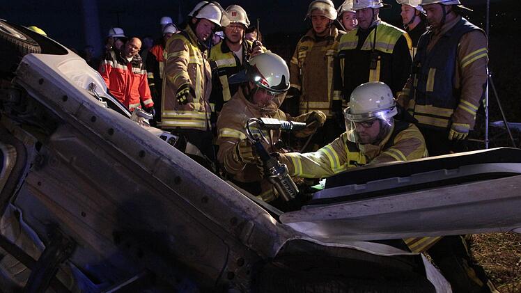 Die Feuerwehrleute setzen das Werkzeug an, um die eingeklemmte Frau aus dem Autowrack zu befreien. Foto: Josef Hofbauer