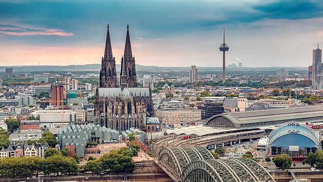 K&ouml;ln Luftaufnahme mit Z&uuml;gen, die auf einer Br&uuml;cke &uuml;ber den Rhein fahren, auf dem Frachtschiffe und Passagierschiffe verkehren. Im Hintergrund der majest&auml;tische K&ouml;lner Dom.  Cologne Aerial view with trains move on a bridge over the Rhine River on which cargo barges and passenger ships ply. Majestic Cologne Cathedral in the background