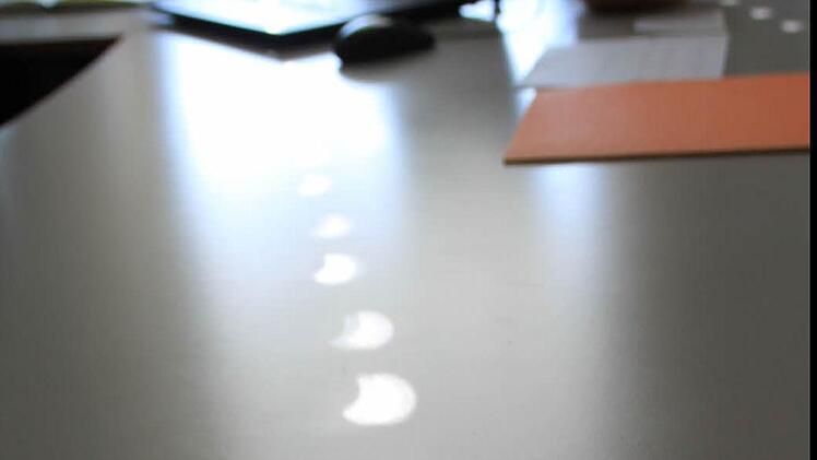 Halbmondförmig fällt das Sonnenlicht durch die kleinen Öffnungen im Rollo auf den Tisch von Direktor Stefan Völker.