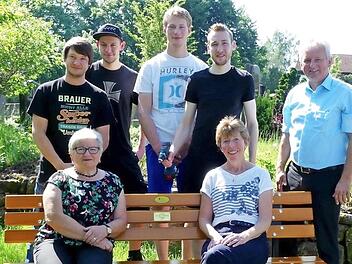 Probesitzen auf der neuen Bank im Friedhof: (vorne, von rechts) Christine Diersch, Brigitte Schröder, dahinter (von rechts) Bürgermeister Werner Diersch und die Vertreter der Strohberta, Christian Kauper, Patrick Munzert, Markus Schoberth und Patrick Hopfer. Foto: Dieter Hübner