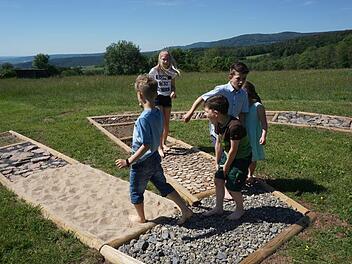 Die Kinder freuen sich über den Barfußpfad. Am meisten schmerzen die  kleine Zapfen und die spitzigen Steine. Foto: Marion Eckert