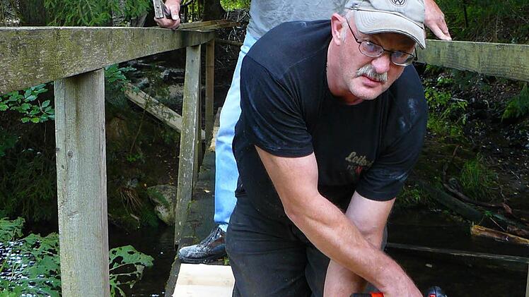 Erst von Wegewart Klaus Hieke (vorne) vorgebohrt, wurden die Bohlenbretter mit den vorhandenen Bohlen vernagelt; im Hintergrund Martin Döring, der seinen Wegewart dabei tatkräftig unterstützte.