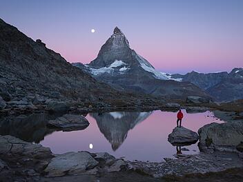 Top-Auswanderungsziele der Deutschen 2025: Das sind die beliebtesten Länder - Matterhorn mit Riffelsee Hiker on a rock in the Riffelsee  at dawn, enjoying the Matterhorn view.