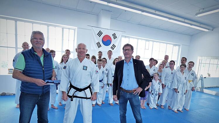 Bei der Übergabe der Geldspende des Rotary-Hilfswerkes Kulmbach (von links) Horst Hohenner, Ralph-Jörg Aman und Peter Bastobbe. Im Hintergrund die Aktiven vom Taekwon-Do Kulmbach e.V. im neuen Trainingszentrum