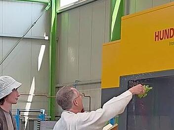 Seelsorger Bernd Keller segnet die neue Maschine, hinter ihm Noah Albert, Enkel der Seniorchefin Hilda Albert.
