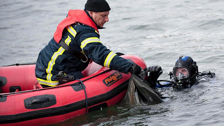 Ein Feuerwehrmann und ein Polizeitaucher holen am 01.11.2012 am Nordufer des Maschsees in Hannover (Niedersachsen) eine Mülltüte an die Wasseroberfläche. Nach dem Fund einer zerstückelten Prostituierten im Maschsee in Hannover hat die Polizei den mutmaßlichen Täter gefasst. Foto: Emily Wabitsch/dpa