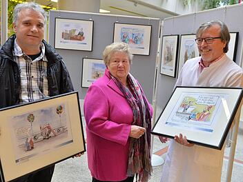 Klaus Nastvogel (links) und Dorothea Fröhlich nahmen aus den Händen von Gerhard Seitz im Foyer des Bamberger Klinikums die Karikaturen entgegen. Fotos: Ronald Rinklef