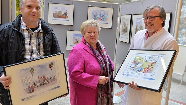 Klaus Nastvogel (links) und Dorothea Fröhlich nahmen aus den Händen von Gerhard Seitz im Foyer des Bamberger Klinikums die Karikaturen entgegen. Fotos: Ronald Rinklef
