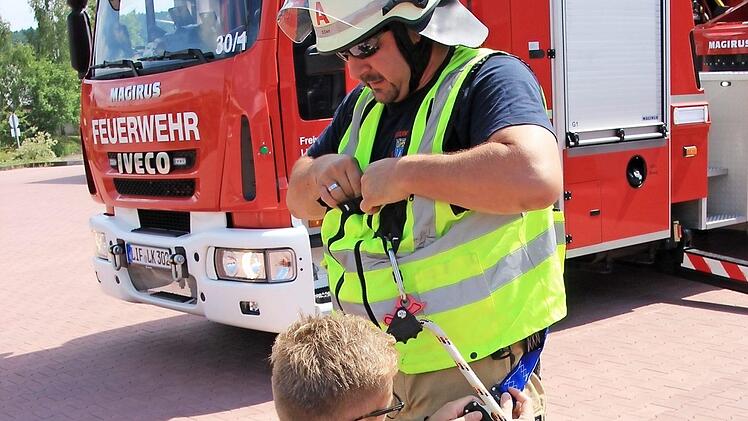 Florian Helmbrecht hilft Daniel Derr, die Sicherungsweste anzulegen, mit der man sich im Korb der Drehleiter einklinkt.
