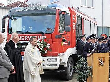 Die Zeiler Feuerwehr mit Kommandant Tobias Hetterich (Rednerpult) war vor dem neuen Auto angetreten, als es übergeben wurde. Mit im Bild, von links: der Zeiler Bürgermeister Thomas Stadelmann, der frühere Gemeindereferent Helmut Leykauf und Pfarrer Michael Erhart.  Foto: ks