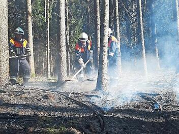 Die Feuerwehrleute löschen Glutnester ab.
