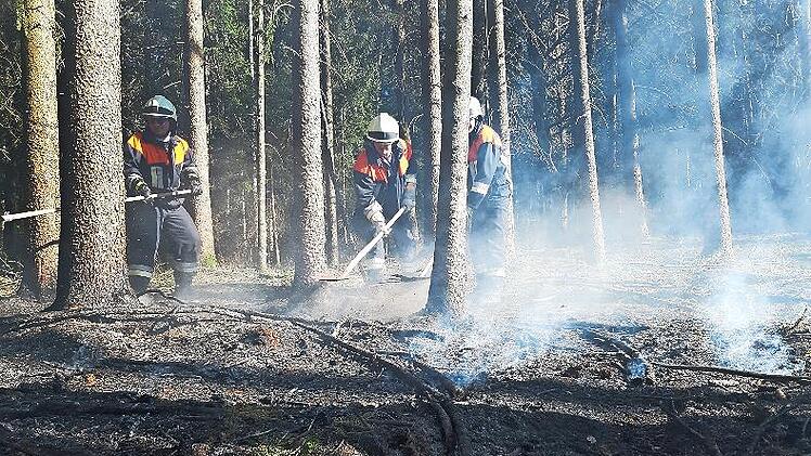 Die Feuerwehrleute löschen Glutnester ab.