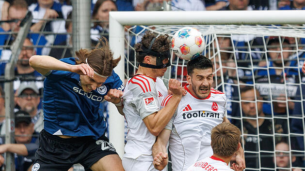 18.04.2026, Nordrhein-Westfalen, Bielefeld: Fu&szlig;ball, M&auml;nner: 2. Bundesliga, Arminia Bielefeld - 1. FC N&uuml;rnberg, 30. Spieltag, Sch&uuml;co Arena. Roberts Uldrikis (Arminia Bielefeld, l) im Kampf um den Ball mit Fabio Gruber (1. FC N&uuml;rnberg, M) und Luka Lochoshvili (1. FC N&uuml;rnberg, r) Foto: Friso Gentsch/dpa - WICHTIGER HINWEIS: Gem&auml;&szlig; den Vorgaben der DFL Deutsche Fu&szlig;ball Liga bzw. des DFB Deutscher Fu&szlig;ball-Bund ist es untersagt, in dem Stadion und/oder vom Spiel angefertigte Fotoaufnahmen in Form von Sequenzbildern und/oder video&auml;hnlichen Fotostrecken zu verwerten bzw. verwerten zu lassen. +++ dpa-Bildfunk +++