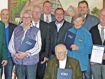 Landratskandidat Sebastian Straubel (rechts), der im Amt bestätigte CSU-Ortsverbandsvorsitzende Richard Bäuerlein (links) und Bürgermeister Michael Keilich (hinten, Mitte), flankiert von Gastrednern sowie für langjährige Treue ausgezeichneten Mitgliedern Foto: Klaus Oelzner