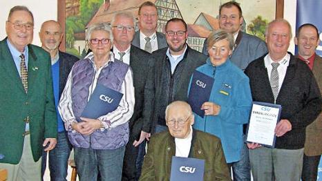 Landratskandidat Sebastian Straubel (rechts), der im Amt bestätigte CSU-Ortsverbandsvorsitzende Richard Bäuerlein (links) und Bürgermeister Michael Keilich (hinten, Mitte), flankiert von Gastrednern sowie für langjährige Treue ausgezeichneten Mitgliedern Foto: Klaus Oelzner