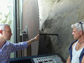 Natursteinwerk-Geschäftsführer Martin Graser (links) erläutert die Arbeitsweise einer Blockkreissäge. Rechts im Bild der Bildhauer Sören Ernst aus Schweinfurt. Foto: Sabine Meißner