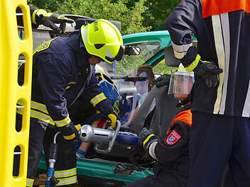 Der Frauenrother Feuerwehrmann Dominik Reichert (links) ist hier mit der Schere dabei, den elfjährigen Luca freizuschneiden. Der Junge wird dabei von einem Schutzschild geschützt. Er sitzt in einem Schrottauto, das im Rahmen einer Feuerwehrübung zerlegt wird. Rechts kniet der Kommandant Georg Grom. Foto: Kathrin Kupka-Hahn