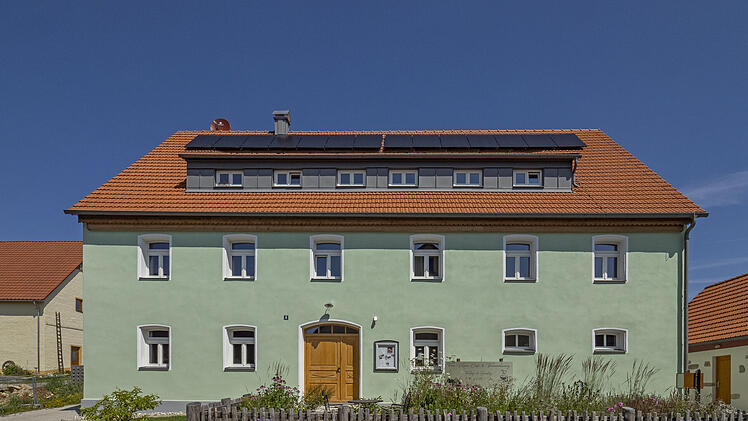 Ein grünes Haus mit grünem Vorgarten