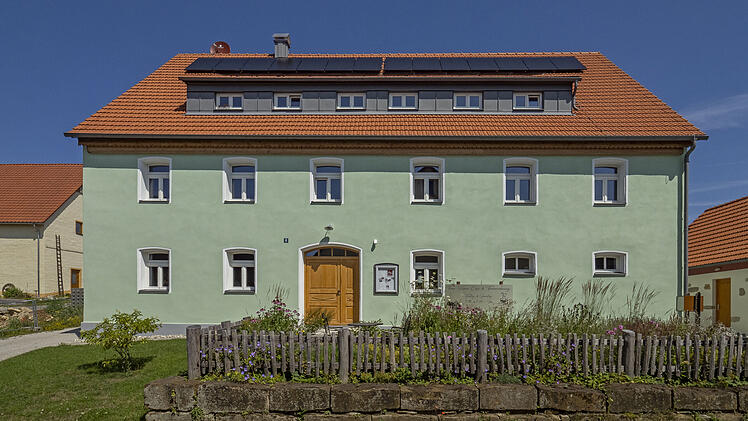Ein grünes Haus mit grünem Vorgarten