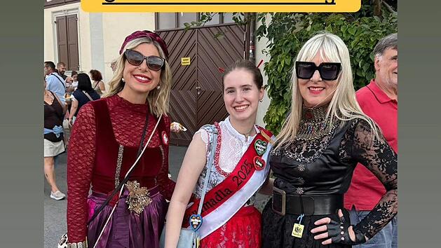 Drei Personen in kreativer Tracht posieren fr&ouml;hlich, inspiriert von "Bamberger Punk-Tracht" des Kaufhaus Schrill in Bamberg. Die Outfits kombinieren traditionelle und moderne Elemente.