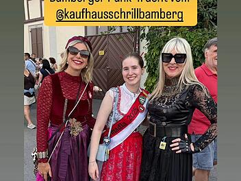 Drei Personen in kreativer Tracht posieren fröhlich, inspiriert von "Bamberger Punk-Tracht" des Kaufhaus Schrill in Bamberg. Die Outfits kombinieren traditionelle und moderne Elemente.