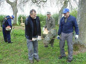 Eine Herausforderung für das "Aufräumteam" aus Großwenkheim war dieser riesige Ast, selbst ein halber Baum. Richard Schleier (von rechts), Martin Ziegler und Günther Behr mussten in Ermangelung einer Motorsäge dem dicken Ast mit einer Handsäge zu Leibe rücken. Links im Bild: Benno Trost, der das hohe Gras schnitt. Foto: Paul Ziegler