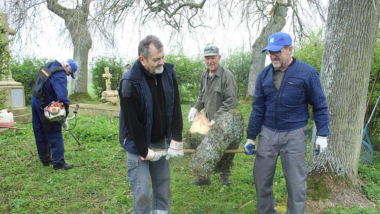 Eine Herausforderung für das "Aufräumteam" aus Großwenkheim war dieser riesige Ast, selbst ein halber Baum. Richard Schleier (von rechts), Martin Ziegler und Günther Behr mussten in Ermangelung einer Motorsäge dem dicken Ast mit einer Handsäge zu Leibe rücken. Links im Bild: Benno Trost, der das hohe Gras schnitt. Foto: Paul Ziegler