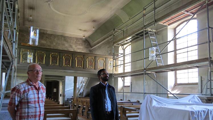 Franz Gundelach und Pater Sony Kochumalayil blicken im dunklen Kirchenschiff auf den Altar. Foto: Doris Bauer