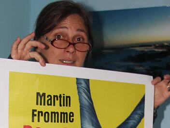 Eva Schreiber-Dümlein mit einem Plakat, das zur Comedy-Lesung mit Martin Fromme einlädt. Foto: Rainer Glissnik