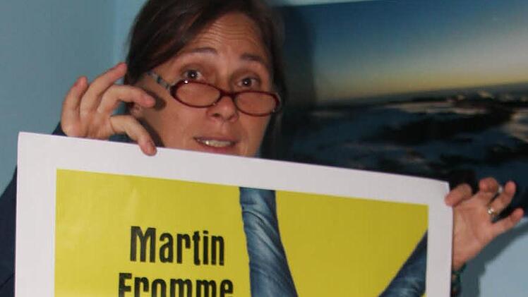 Eva Schreiber-Dümlein mit einem Plakat, das zur Comedy-Lesung mit Martin Fromme einlädt. Foto: Rainer Glissnik