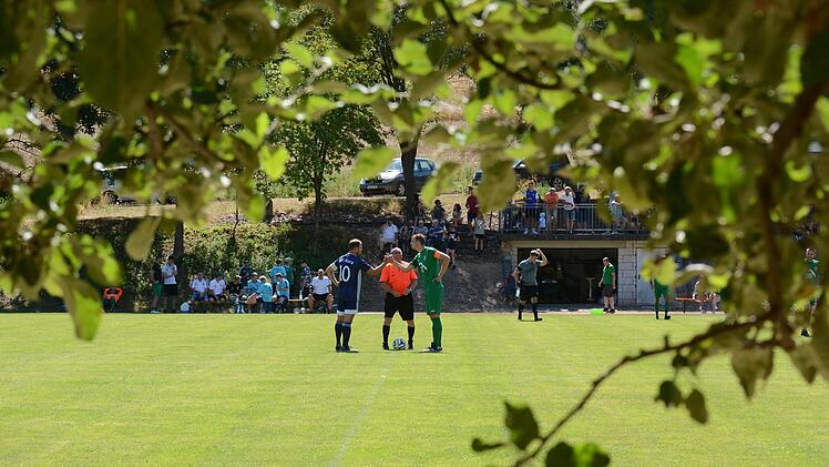 Beschauliche Derby-Atmosphäre in Machtilshausen mit Schiedsrichter Theo Marschall sowie den Kapitänen Florian Schießer (links) vom SV Aura und Valentim Saum. Foto: ssp