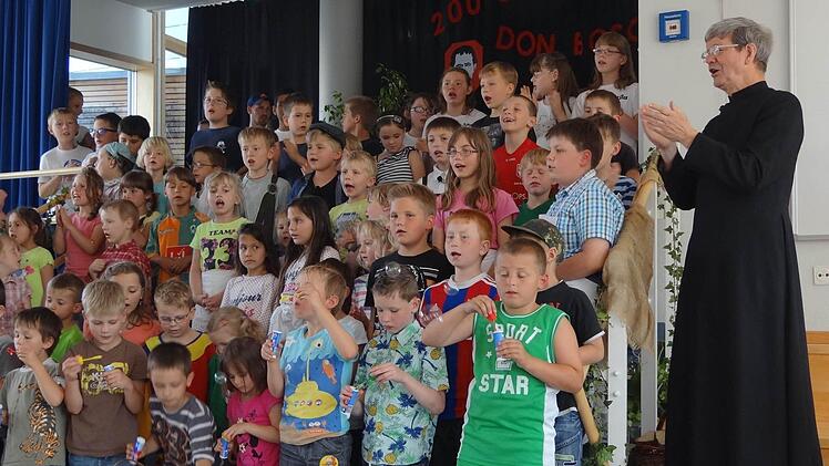 Alle Kinder der Tagesstätte und des Förderzentrums präsentierten sich am Schulfest auf der Bühne. Mit dabei war auch Pater Alfons Blüml (rechts). Foto: Johanna Eckert