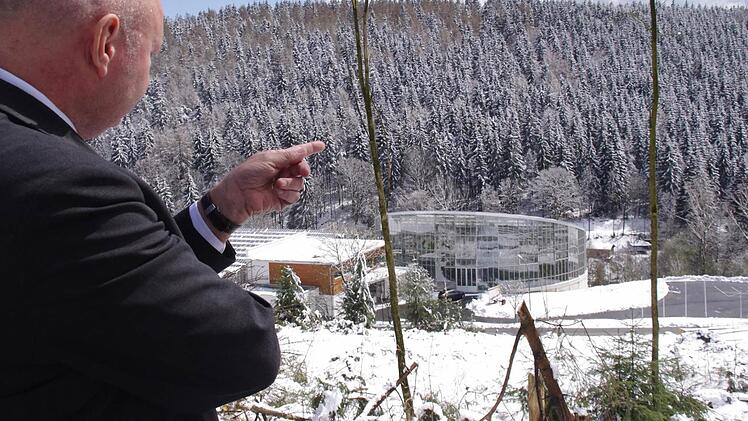 Bürgermeister Peter Ebertsch freut sich über die Zertifizierung des Tropenhauses und zeigt vor sich auf die neuerdings freigelegte Waldfläche oberhalb des gläsernen Bauwerks. Foto: Marco Meißner