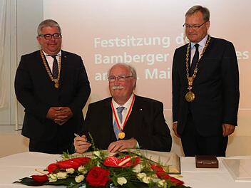 Nachdem er die Bürgermedaille in Empfang genommen hatte, trug sich der frühere Regierungspräsident Wilhelm Wenning in das Goldene Buch der Stadt Bamberg ein. Rechts Oberbürgermeister Andreas Starke, links Bürgermeister Wolfgang Metzner  Foto: Barbara Herbst