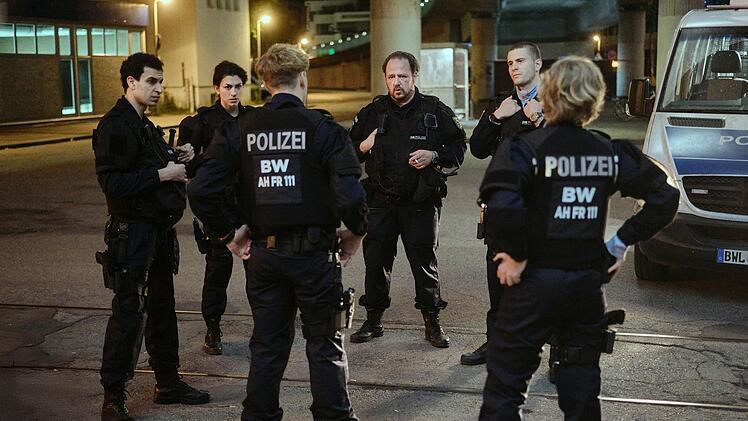 Sechs Bereitschaftspolizisten diskutieren, was sie in der Diskothek erlebt haben. Einsatzleiter Wolle Heizmann (Andreas Anke, dritter von links) ist sich uneins mit Mahmoud (Mouataz Alshaltouh, links), Mariam (Anna Bardavelidze, zweite von links), Jakub (Lasse Lehmann, dritter von links), Timo (Ben Felipe) und Pia (Caroline Hellwig).
