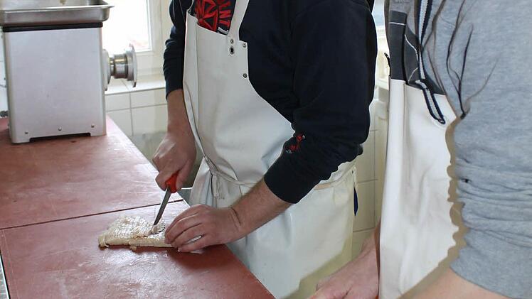 Constantin Wüstenberg und Sebastian Wagner (von rechts) schneiden Schwarte und Fleisch für die Blut- und Leberwürste klein.