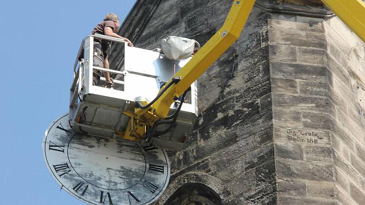 Jürgen Balbach hat das verwitterte Zifferblatt an der Südseite des Glockenturms der Kronacher Christuskirche abgenommen.  Fotos: Friedwald Schedel