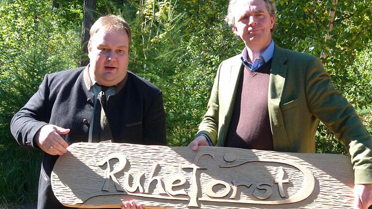 Frank Zulauf von der Ruheforst Deutschland GmbH (links) überreicht Heinrich Graf zu Ortenburg (rechts) eine neue Begrüßungstafel.Foto: Lothar Weidner