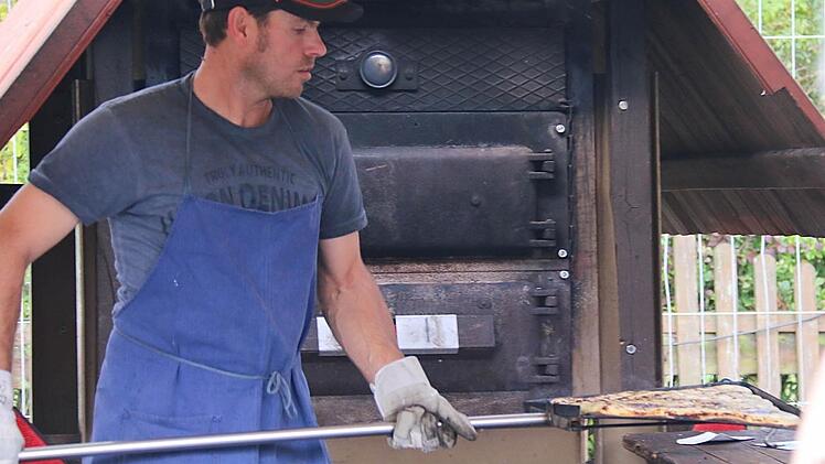 Valeri Strasheim öffnet die Ofentüre und schwingt den dampfenden Zwiebelplootz auf dem Holzbrett mit dem langen Stiel auf den Tisch. Fotos: Gerd Schaar