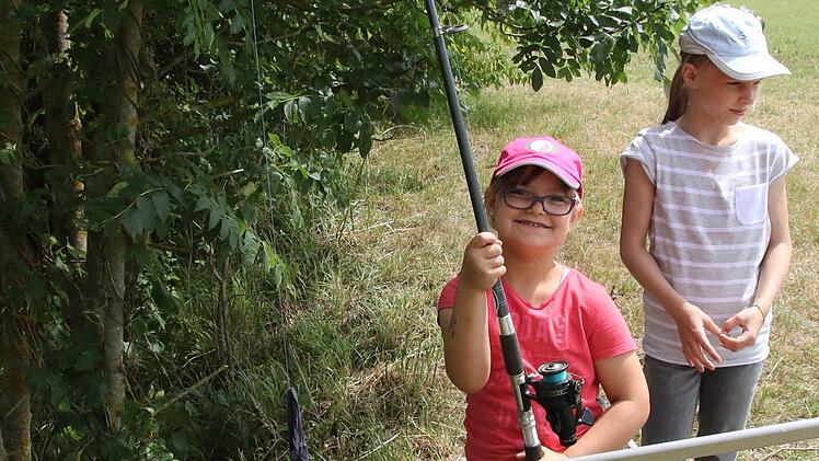 Emma Kanzler zieht eine Angel aus dem Wasser, an der ein Strumpf, mit einem Köder befestigt, war. Dahinter Melanie Kob Foto: Michael Stelzner