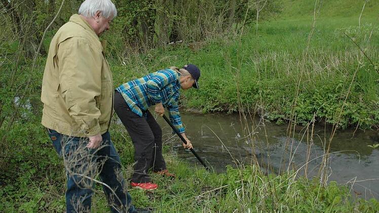Dorothea Schaal versucht, im Ketschenbach das Sieb für den Wasserzufluss des Kneippbeckens zu reinigen. Bernd Ramster steht ihr fachkundig zur Seite. Foto: Edwin Meißinger