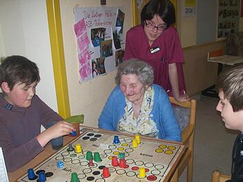 Die Firmlinge Georg Scherbel und Max Schneider beim Spielen mit der Bewohnerin Gunda Biesenecker im ASB-Seniorenheim. Im Hintergrund Gerontofachkraft Ute Seelow vom ASB-Seniorenheim. Foto: K.-H. Hofmann