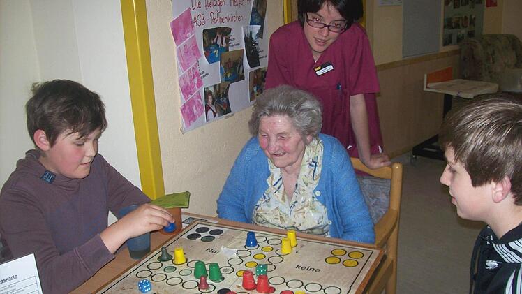 Die Firmlinge Georg Scherbel und Max Schneider beim Spielen mit der Bewohnerin Gunda Biesenecker im ASB-Seniorenheim. Im Hintergrund Gerontofachkraft Ute Seelow vom ASB-Seniorenheim. Foto: K.-H. Hofmann